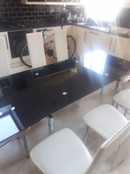 Black glass table and 8 cream chairs extends to fit 8 chairs aroud or have it as 6 seater 450 euro