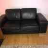 Two black leather two seater sofas for sale 